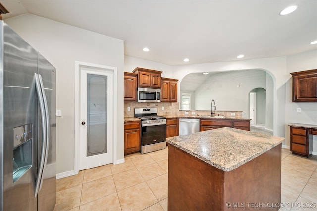 9241 N 144th E Ave, Owasso, OK 74055 - kitchen with stainless steel appliances, arched walkways, a sink, decorative backsplash, and light tile patterned floors