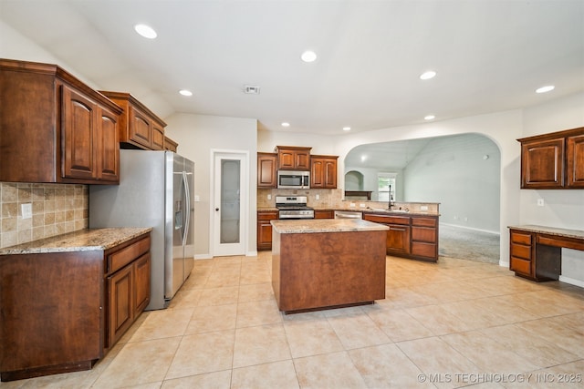 9241 N 144th E Ave, Owasso, OK 74055 - kitchen featuring stainless steel appliances, arched walkways, a sink, decorative backsplash, and light tile patterned floors