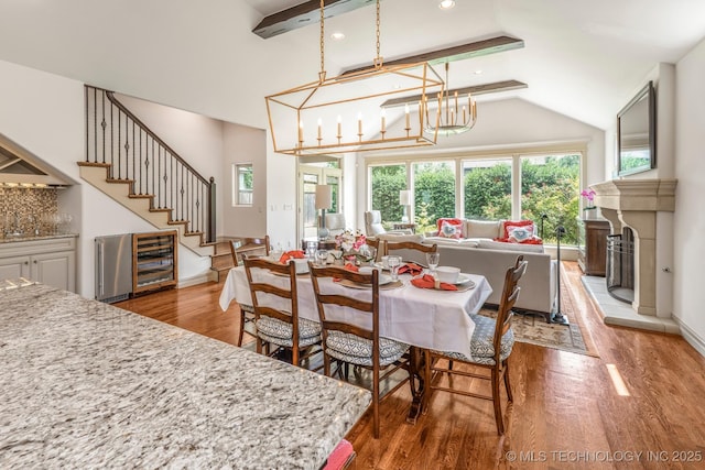 1412 E 37th St, Tulsa, OK 74105 - dining space featuring light wood finished floors, a chandelier, beverage cooler, lofted ceiling, and stairway