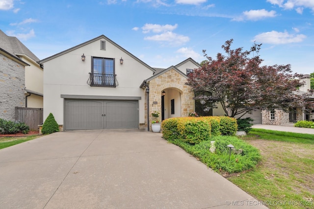 1412 E 37th St, Tulsa, OK 74105 - french country style house with stone siding, concrete driveway, a balcony, stucco siding, and a garage