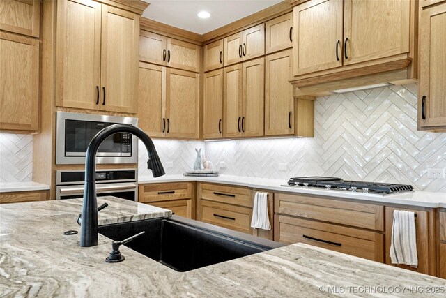 3406 W Quantico Pl, Broken Arrow, OK 74011 - kitchen featuring appliances with stainless steel finishes, light stone countertops, backsplash, a sink, and light brown cabinets