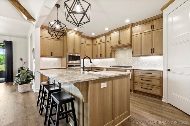 3406 W Quantico Pl, Broken Arrow, OK 74011 - kitchen with stainless steel microwave, a sink, dark wood-type flooring, a breakfast bar area, and an island with sink
