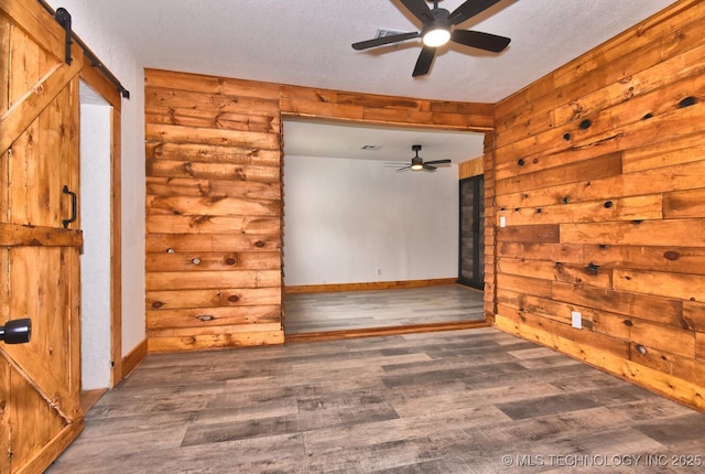 206 S Mounds St, Sapulpa, OK 74066 - unfurnished room featuring a ceiling fan, wood finished floors, a barn door, and rustic walls