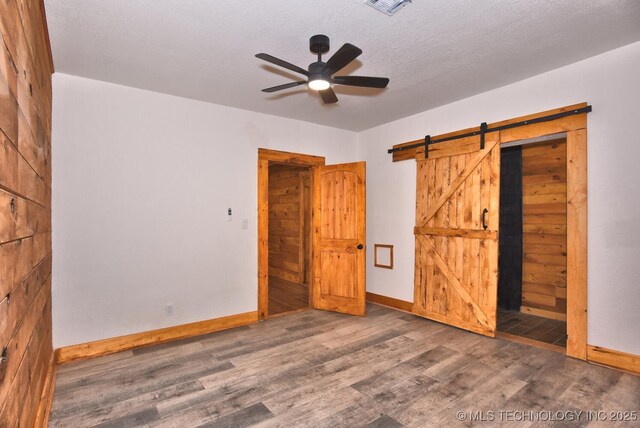 206 S Mounds St, Sapulpa, OK 74066 - unfurnished bedroom with wood finished floors, baseboards, a barn door, and ceiling fan