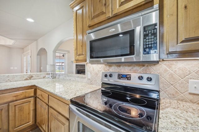 6200 E 340th Rd, Talala, OK 74080 - kitchen featuring stainless steel appliances, arched walkways, backsplash, and light stone counters
