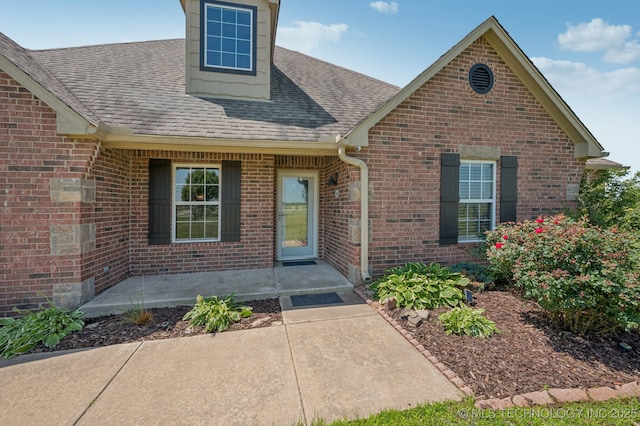 6200 E 340th Rd, Talala, OK 74080 - property entrance with roof with shingles, brick siding, and a patio area
