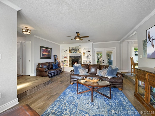402 Beaumont Dr, Ardmore, OK 73401 - living area featuring a textured ceiling, wood finished floors, ceiling fan, crown molding, and a warm lit fireplace