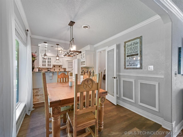 402 Beaumont Dr, Ardmore, OK 73401 - dining area with dark wood-style floors, arched walkways, ornamental molding, and a textured ceiling