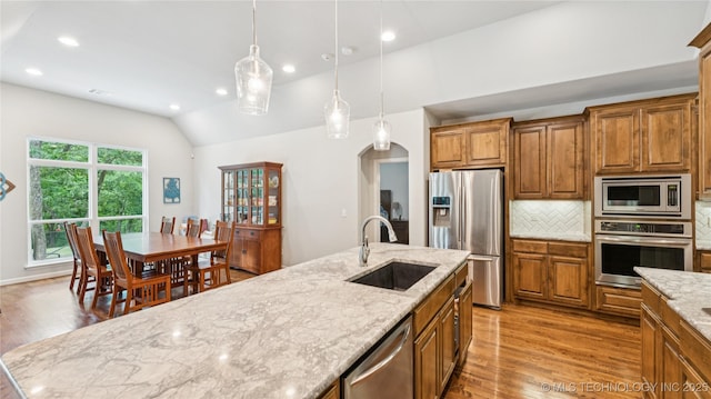 11602 S 30th W Ave, Jenks, OK 74037 - kitchen with appliances with stainless steel finishes, a sink, brown cabinetry, lofted ceiling, and light wood-style flooring
