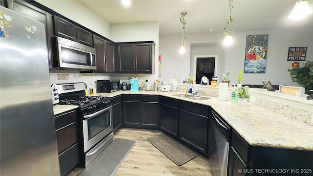 5752 E 147th St S, Bixby, OK 74008 - kitchen featuring appliances with stainless steel finishes, light wood finished floors, a peninsula, a sink, and light stone countertops