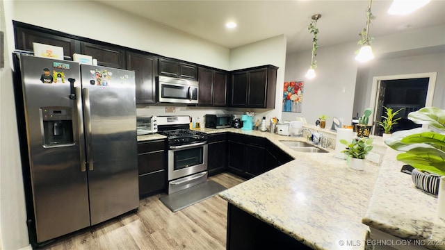5752 E 147th St S, Bixby, OK 74008 - kitchen with stainless steel appliances, a sink, light wood-type flooring, a peninsula, and light stone counters
