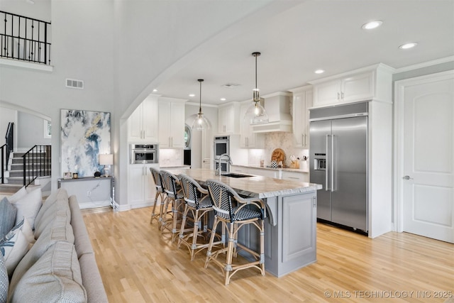 18319 E Red Fox Trl, Owasso, OK 74055 - kitchen with stainless steel built in refrigerator, arched walkways, a sink, light wood-style floors, and recessed lighting
