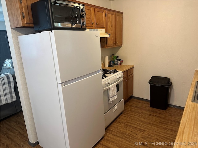 206 I St NE, Ardmore, OK 73401 - kitchen with white appliances, dark wood finished floors, brown cabinetry, light countertops, and under cabinet range hood