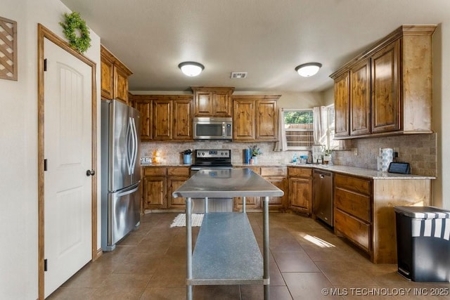 233 Murray Pl, Mannford, OK 74044 - kitchen with stainless steel appliances, brown cabinets, decorative backsplash, and dark tile patterned flooring