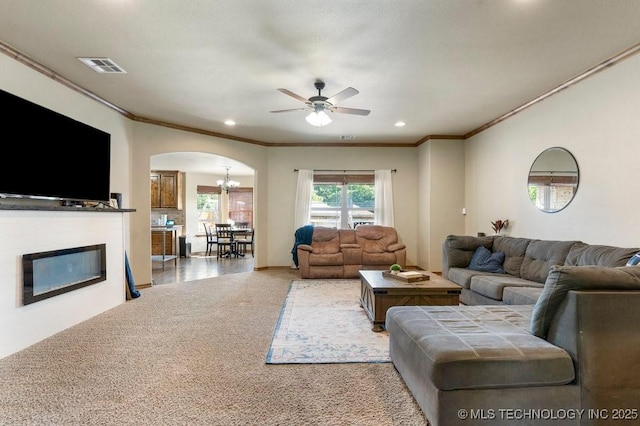 233 Murray Pl, Mannford, OK 74044 - carpeted living room with arched walkways, crown molding, a ceiling fan, a glass covered fireplace, and recessed lighting