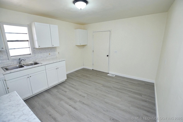 215 S Maple Ave, Tahlequah, OK 74464 - kitchen featuring a sink, white cabinetry, decorative backsplash, light countertops, and light wood-type flooring