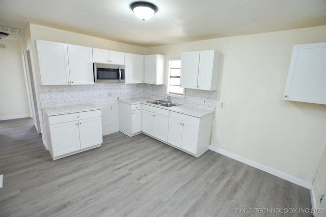 215 S Maple Ave, Tahlequah, OK 74464 - kitchen featuring stainless steel microwave, a sink, backsplash, and baseboards