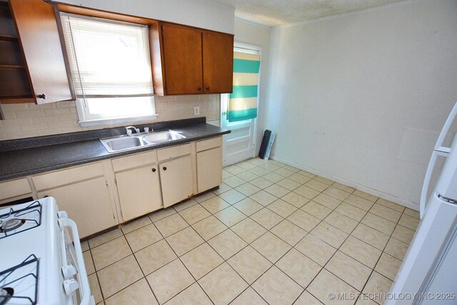 215 S Maple Ave, Tahlequah, OK 74464 - kitchen featuring a sink, white gas range, dark countertops, backsplash, and light tile patterned floors