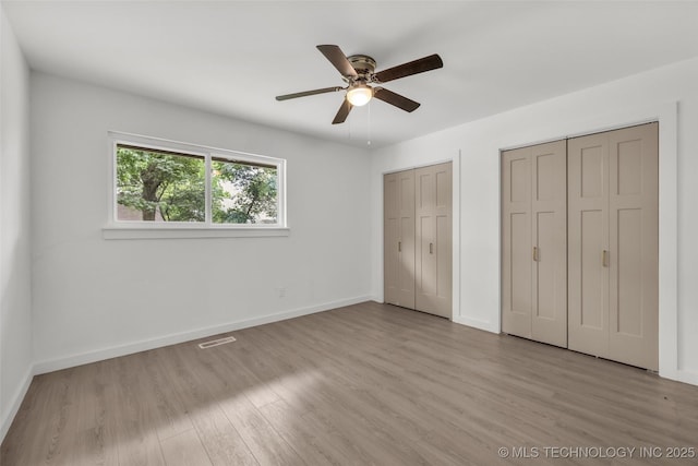 7362 S 68th E Ave, Tulsa, OK 74133 - unfurnished bedroom with multiple closets, light wood-style floors, baseboards, and ceiling fan