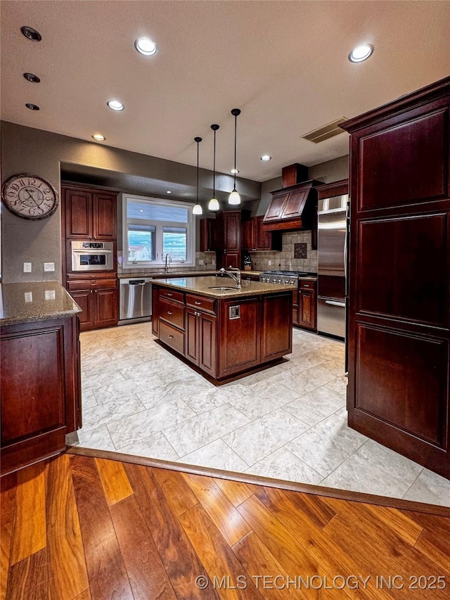 4418 N Little, Cushing, OK 74023 - kitchen with stainless steel appliances, premium range hood, a sink, tasteful backsplash, and a kitchen island with sink