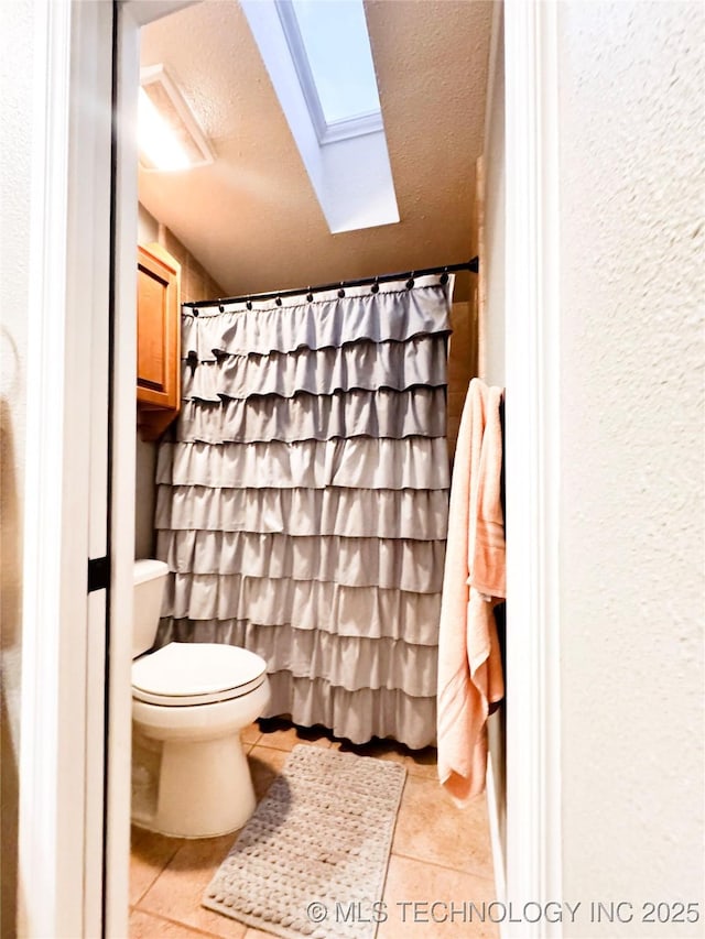 4418 N Little, Cushing, OK 74023 - full bathroom featuring a skylight, toilet, tile patterned floors, a textured ceiling, and a textured wall