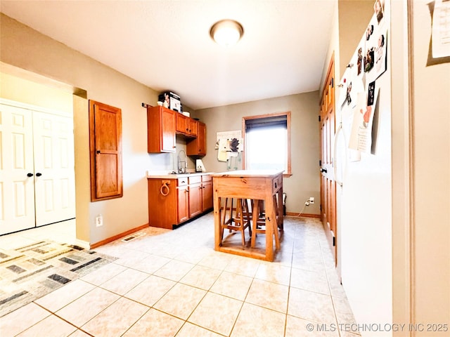 4418 N Little, Cushing, OK 74023 - kitchen featuring light countertops, a sink, light tile patterned flooring, and a breakfast bar