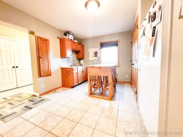 4418 N Little, Cushing, OK 74023 - kitchen featuring light countertops, baseboards, a kitchen bar, and light tile patterned floors