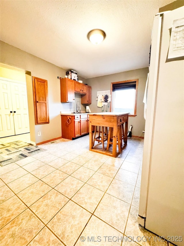 4418 N Little, Cushing, OK 74023 - kitchen with a sink, baseboards, light countertops, freestanding refrigerator, and light tile patterned flooring