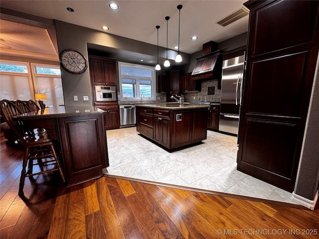 4418 N Little, Cushing, OK 74023 - kitchen with stainless steel appliances, a center island with sink, light wood-style floors, a kitchen breakfast bar, and recessed lighting