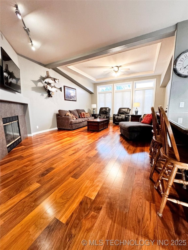 4418 N Little, Cushing, OK 74023 - living room with hardwood / wood-style flooring, a tiled fireplace, a ceiling fan, rail lighting, and baseboards