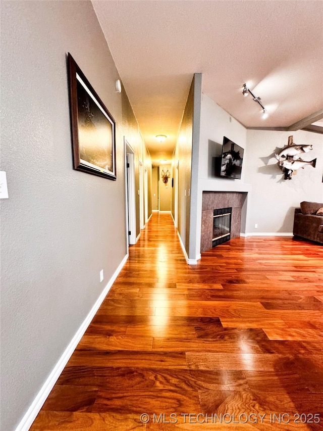 4418 N Little, Cushing, OK 74023 - corridor featuring wood finished floors, baseboards, a textured ceiling, and rail lighting