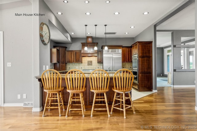 4418 N Little, Cushing, OK 74023 - kitchen featuring appliances with stainless steel finishes, a peninsula, recessed lighting, light wood-style floors, and a kitchen breakfast bar