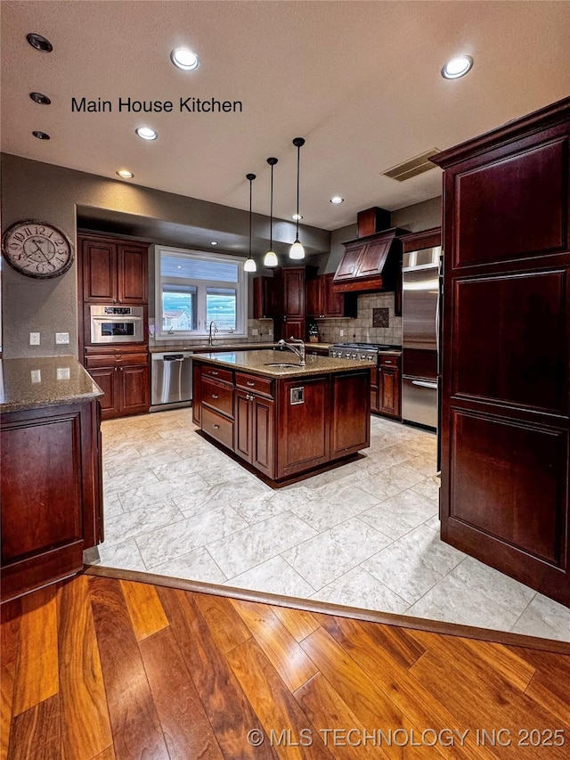 4418 N Little, Cushing, OK 74023 - kitchen with appliances with stainless steel finishes, custom exhaust hood, backsplash, stone counters, and an island with sink