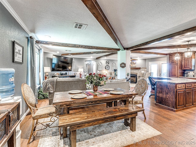 830294 S 3530, Stroud, OK 74079 - dining space featuring a textured ceiling, a fireplace, light wood finished floors, beam ceiling, and crown molding