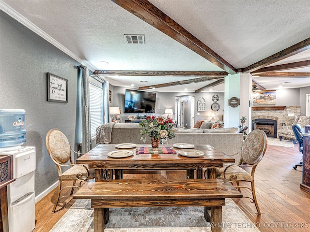 830294 S 3530, Stroud, OK 74079 - dining space featuring a textured ceiling, a textured wall, light wood finished floors, crown molding, and a fireplace with raised hearth