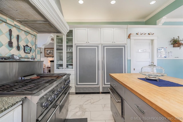 211 F SW, Ardmore, OK 73401 - kitchen featuring gas stove, light marble finish floors, white cabinetry, crown molding, and custom range hood