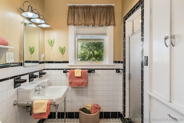 211 F SW, Ardmore, OK 73401 - full bathroom with tile walls, a shower stall, a wainscoted wall, and a sink