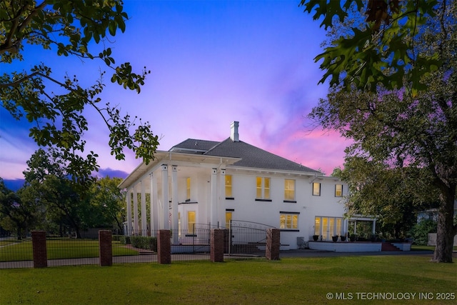 211 F SW, Ardmore, OK 73401 - back of house at dusk featuring a chimney and a shingled roof