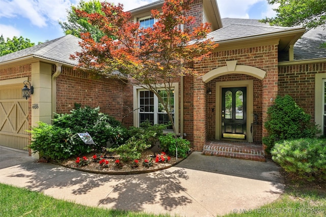 11586 S 66th E Ave, Bixby, OK 74008 - view of exterior entry featuring brick siding, an attached garage, and a shingled roof