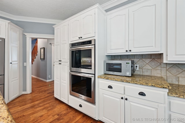 11586 S 66th E Ave, Bixby, OK 74008 - kitchen featuring stainless steel double oven, white microwave, tasteful backsplash, white cabinetry, and wood finished floors