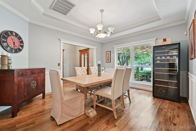 11586 S 66th E Ave, Bixby, OK 74008 - dining area featuring beverage cooler, a chandelier, a tray ceiling, wood finished floors, and ornamental molding