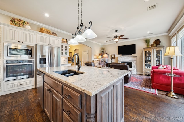 13234 S 68th E Ave, Bixby, OK 74008 - kitchen with stainless steel appliances, a sink, arched walkways, a stone fireplace, and a ceiling fan