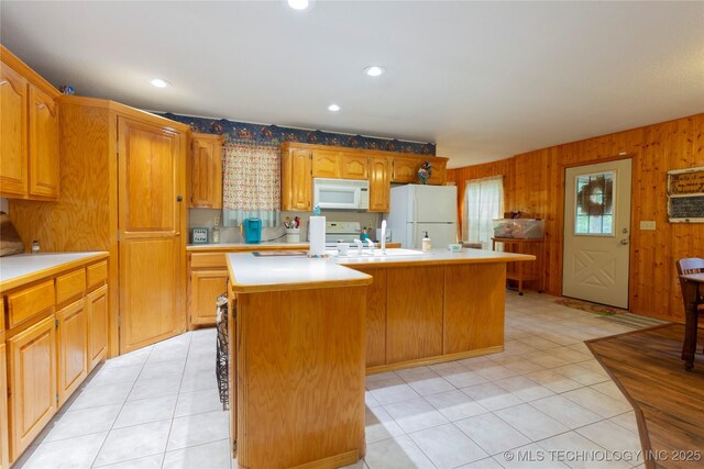 162 Dolittle Ln, Mcalester, OK 74501 - kitchen featuring white appliances, light countertops, a center island with sink, light tile patterned floors, and wood walls