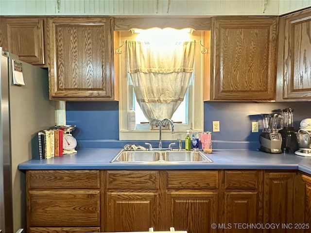 1327 E 10th St, Okmulgee, OK 74447 - kitchen with brown cabinetry and freestanding refrigerator