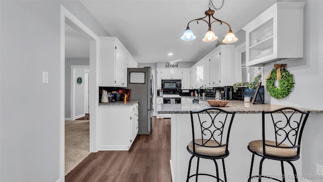 6063 Wilson, Durant, OK 74701 - kitchen with black appliances, a peninsula, white cabinetry, dark wood-style flooring, and a chandelier