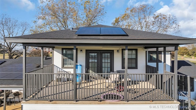 6063 Wilson, Durant, OK 74701 - back of property featuring roof mounted solar panels, roof with shingles, and a porch