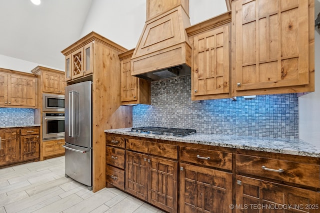 15303 Foreacre Cir, Sapulpa, OK 74066 - kitchen featuring appliances with stainless steel finishes, custom range hood, light stone counters, and backsplash