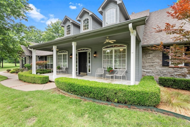 5070 Lake Breeze Rd, Grove, OK 74344 - new england style home featuring a porch, ceiling fan, a front yard, and roof with shingles