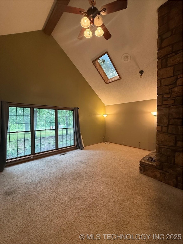 1808 N Woodland, Drumright, OK 74030 - unfurnished living room with carpet, high vaulted ceiling, a ceiling fan, a skylight, and beamed ceiling