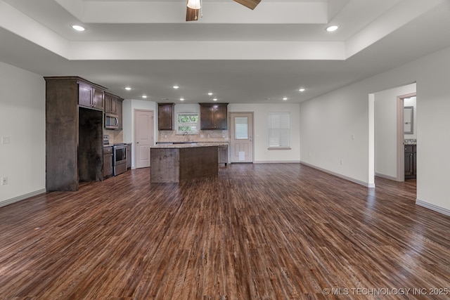 3923 Bryan Rd, Durant, OK 74701 - unfurnished living room featuring dark wood finished floors, a raised ceiling, baseboards, recessed lighting, and a sink